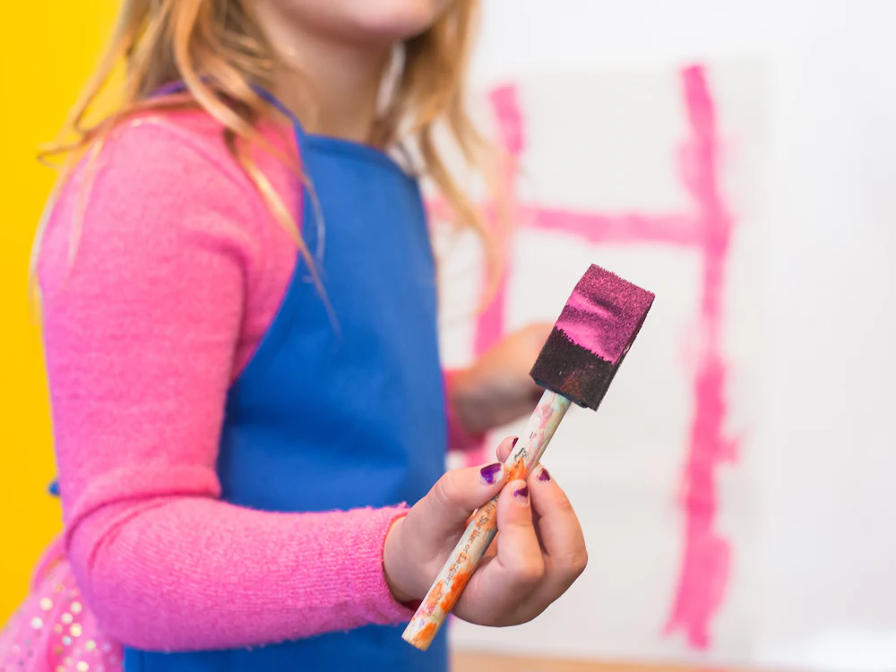 Menina a pintar com uma trincha