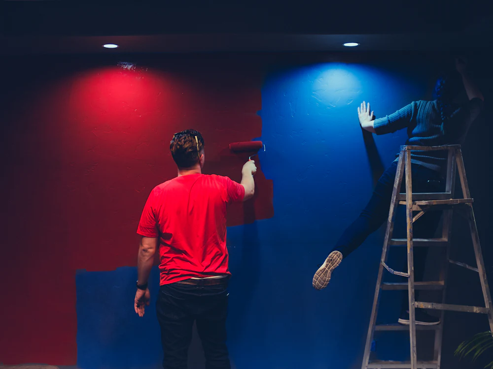 Duas pessoas a pintar paredes de vermelho e azul